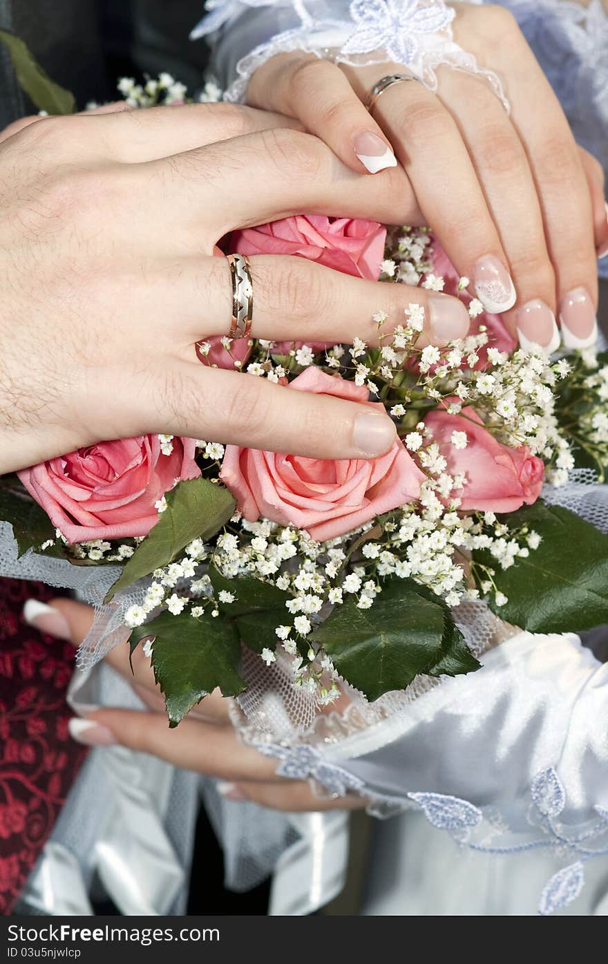 Hands and rings on wedding bouquet