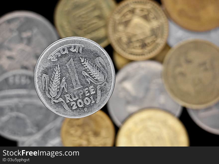 One rupee coin and other coins isolated on black