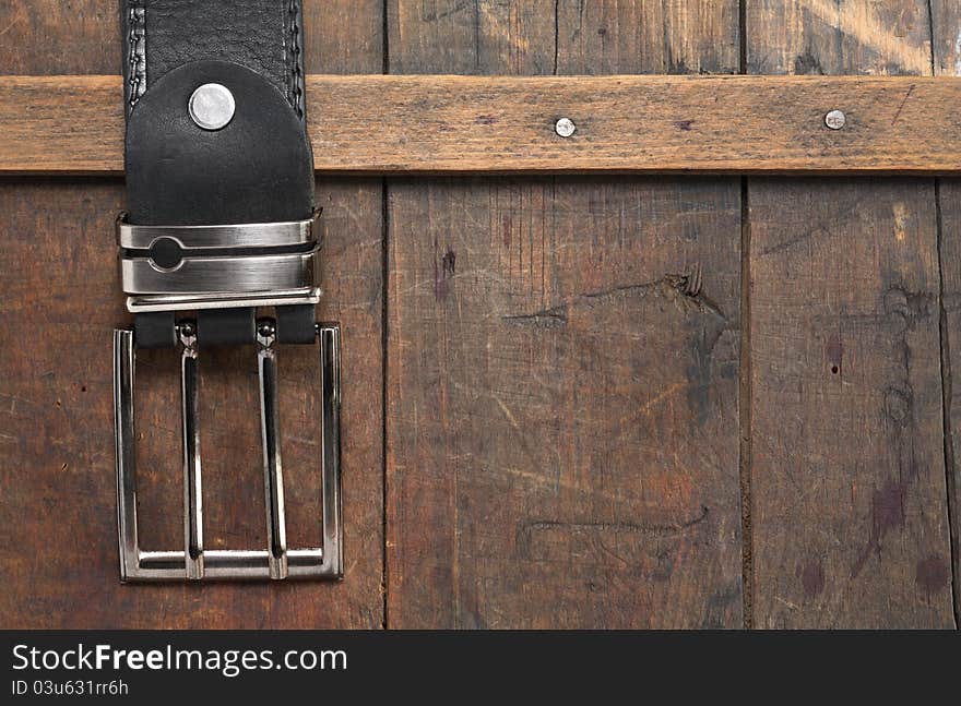 Closeup of black leather belt hanging on old wooden background. Closeup of black leather belt hanging on old wooden background