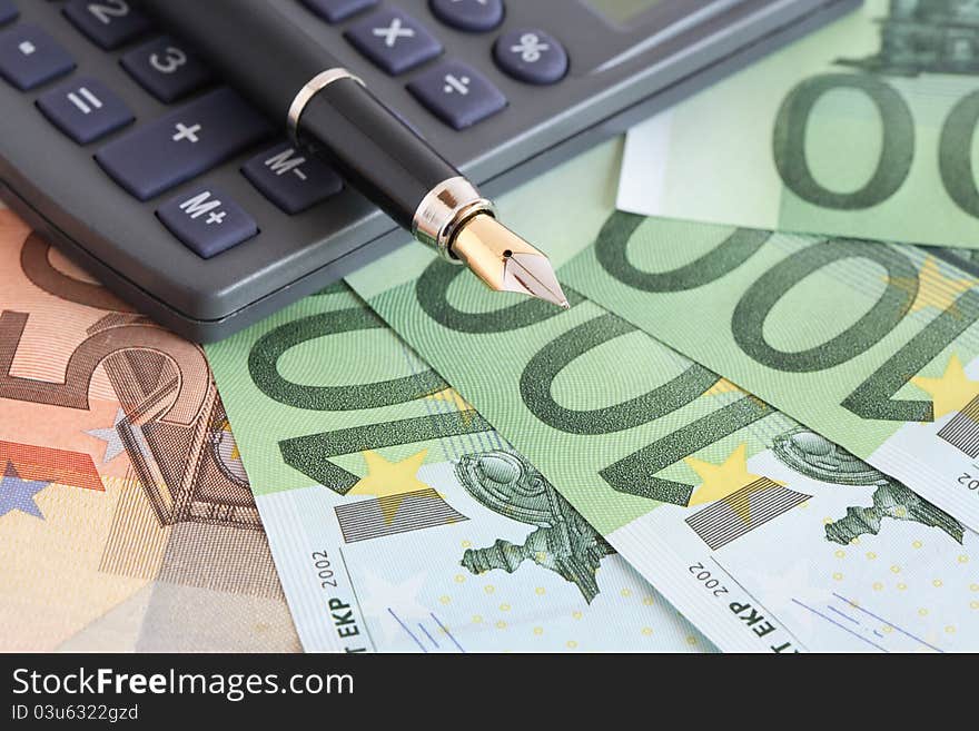 Business concept. Closeup of fountain pen and calculator on european currency background. Business concept. Closeup of fountain pen and calculator on european currency background