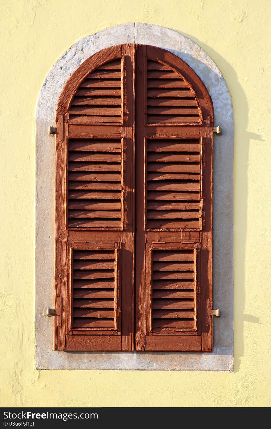 An old brown wooden window of the yellow wall. An old brown wooden window of the yellow wall