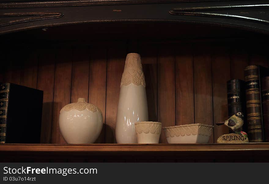 Books and vase on a shelf of old fashion ornamented wood