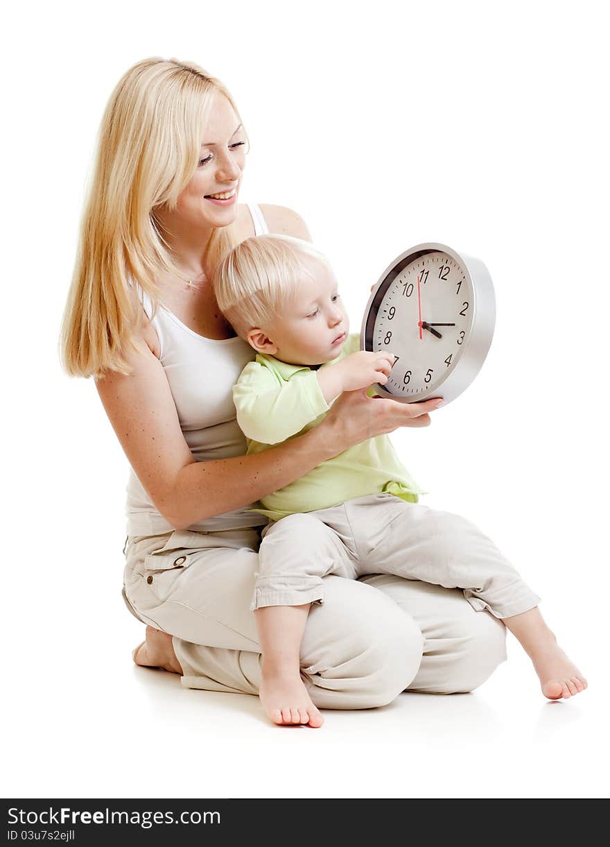 Mother displaying time to her son seating together on floor in studio