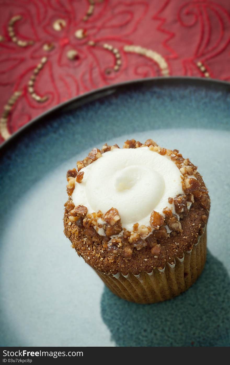 Carrot muffin with nuts and vanilla buttercream on green plate. Carrot muffin with nuts and vanilla buttercream on green plate