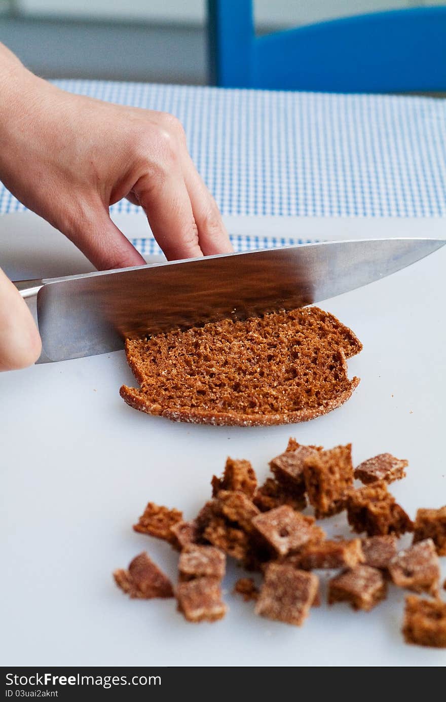 A chef cutting a piece of rye bread for croutons in preparation for cooking. A chef cutting a piece of rye bread for croutons in preparation for cooking.