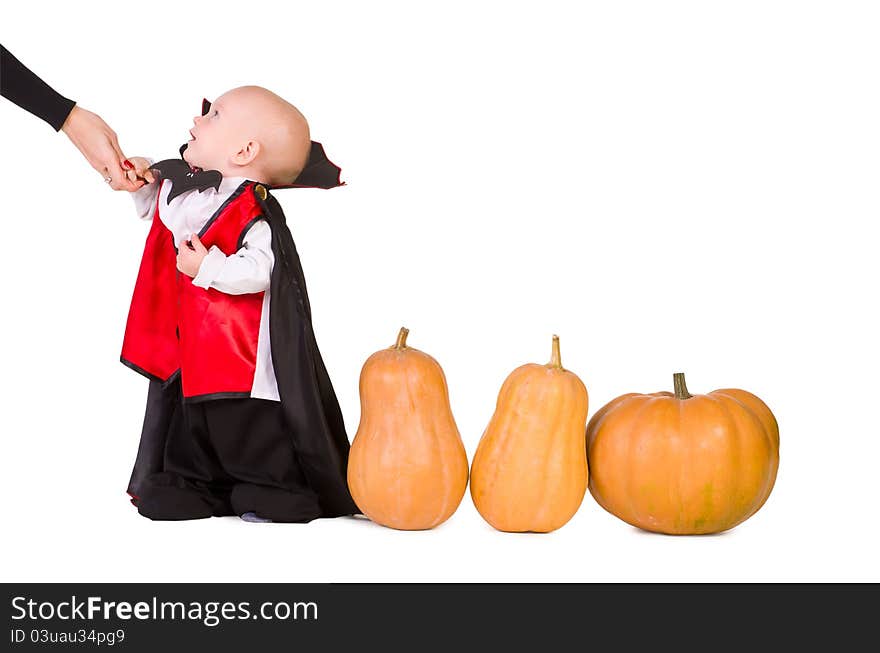 Little baby boy standing in black halloween cloak near pumpkins, isolated on a white background. Little baby boy standing in black halloween cloak near pumpkins, isolated on a white background