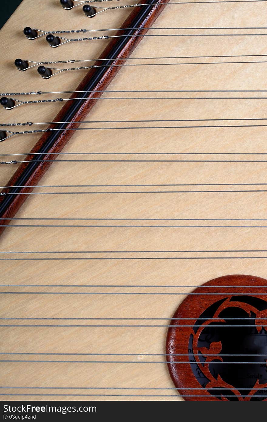 Hand made hammer dulcimer made of wood and multiple strings with intricate scroll-work