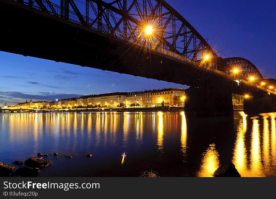 Railroad bridge over the river in the city after sunset