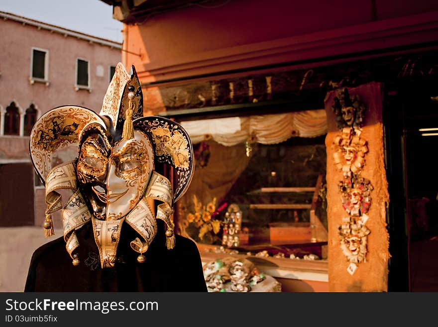 Doll portrait with vemetian gold black and white mask and beautifull shop behind the doll, Venice, Italy. Doll portrait with vemetian gold black and white mask and beautifull shop behind the doll, Venice, Italy