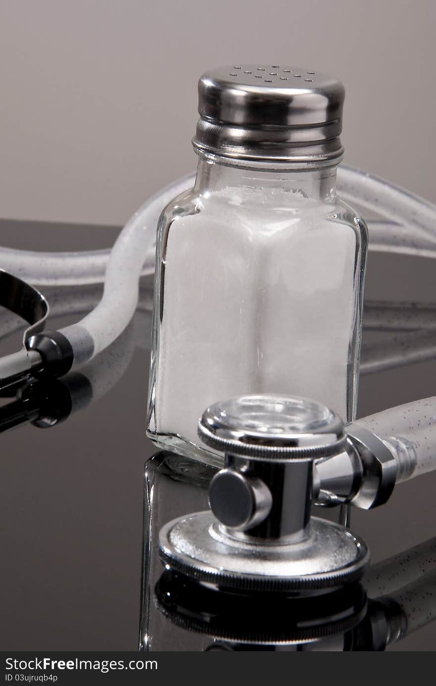 Salt shaker on black counter with stehtoscope. Salt shaker on black counter with stehtoscope