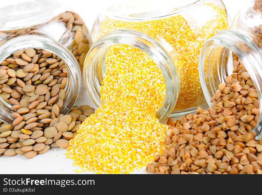 Three open glass jars with lentils, corn grits and buckwheat