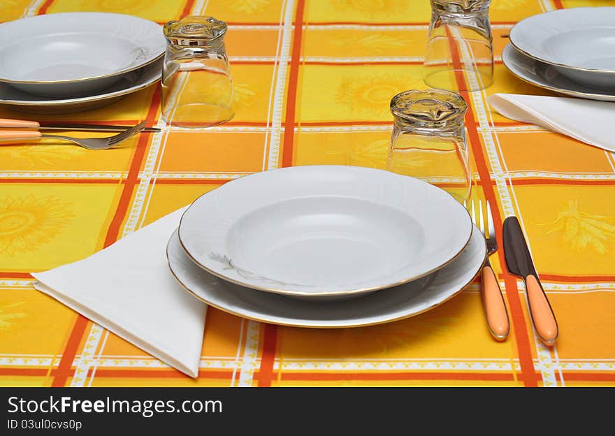 Dressed table for three with orange table cloth. Dressed table for three with orange table cloth