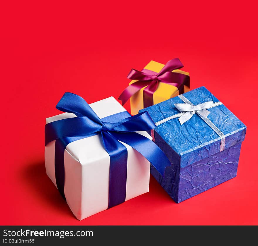 Three boxes with gifts on red background.