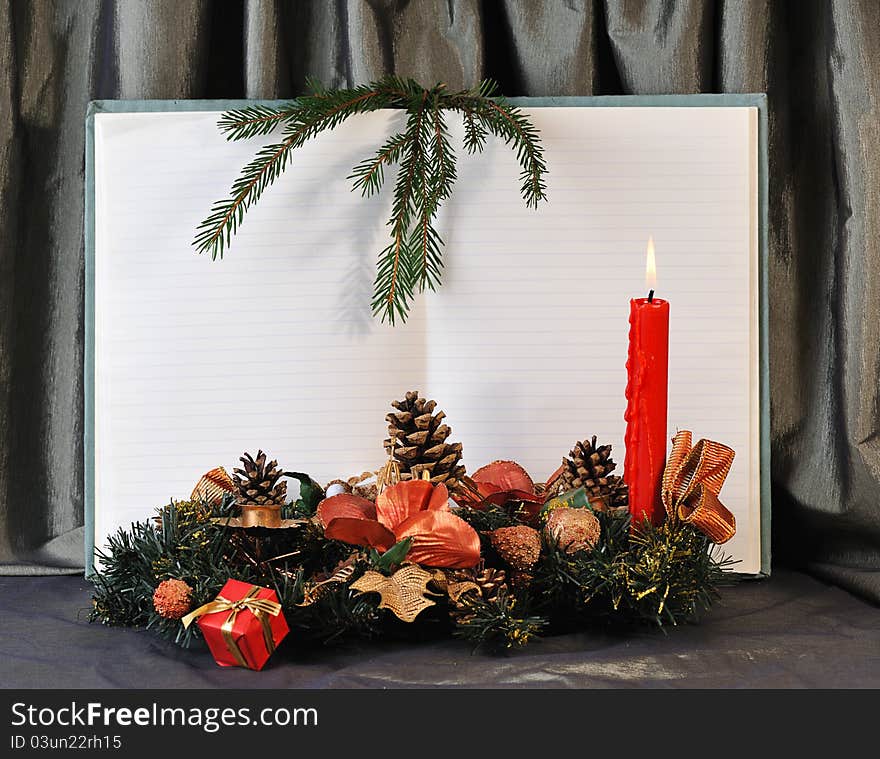 Blank pages of old open notebook bordering with christmas decoration and red burn candle. Blank pages of old open notebook bordering with christmas decoration and red burn candle