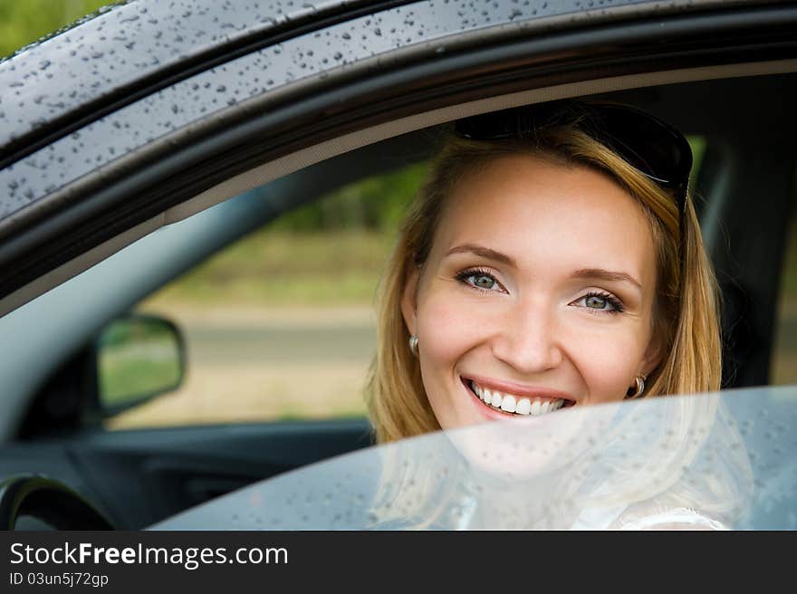 Portrait of attractive young smiling woman in the new car  - outdoors