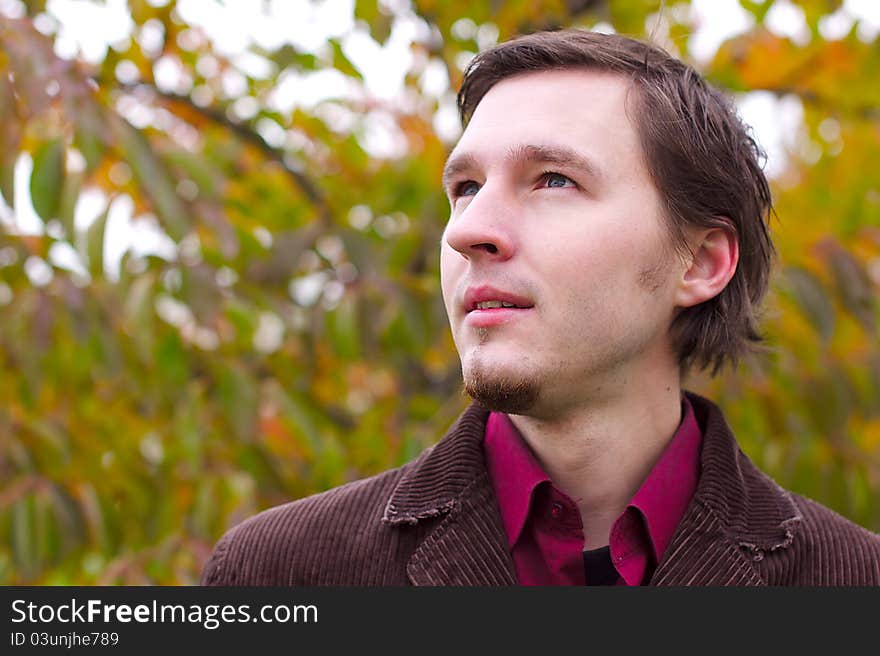 Handsome man portrait in autumn leaves background. Man with a little beard.