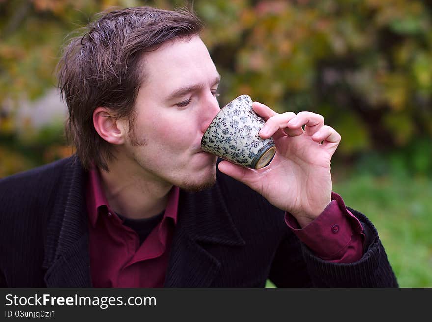 Handsome man drinking tea outdoors