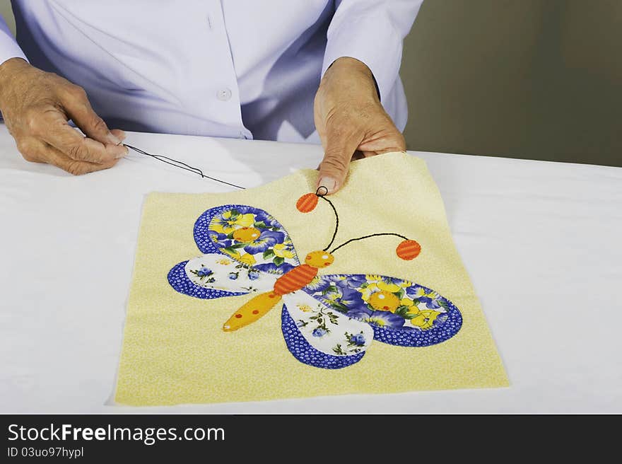 A woman chain stitching fabric to make butterfly squares. A woman chain stitching fabric to make butterfly squares.