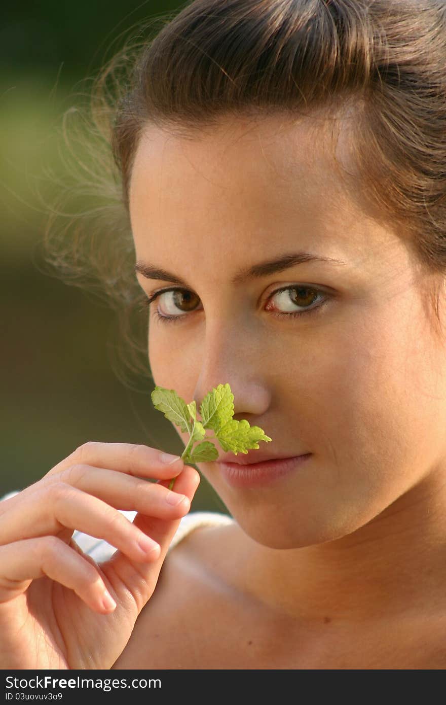 Beautiful young girl smelling melissa leaf