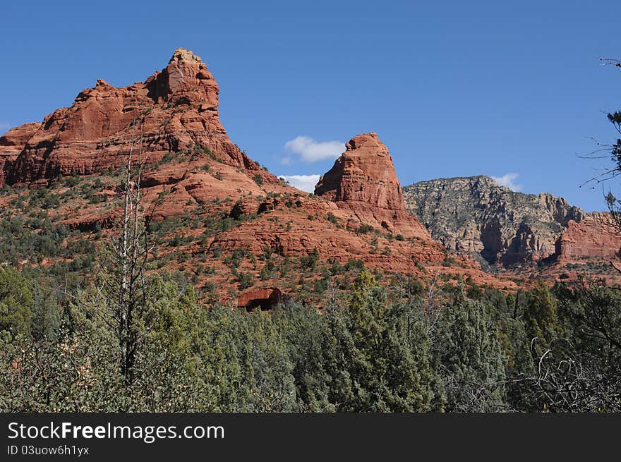 View of pillars of stone in Sedonna Arizona, gradient colors of stone, red rocks at the base and pale white at the summits, low shrub bush on the base. View of pillars of stone in Sedonna Arizona, gradient colors of stone, red rocks at the base and pale white at the summits, low shrub bush on the base