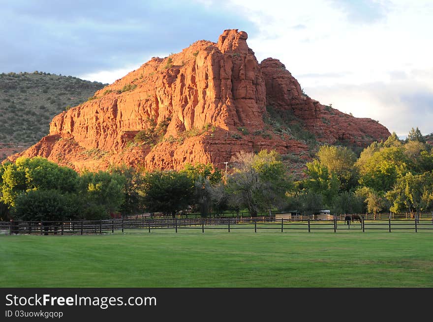 Green lush meadow with horses grazing and a picket rail frence.
Large stone pinnacle rises in the middle. Green lush meadow with horses grazing and a picket rail frence.
Large stone pinnacle rises in the middle