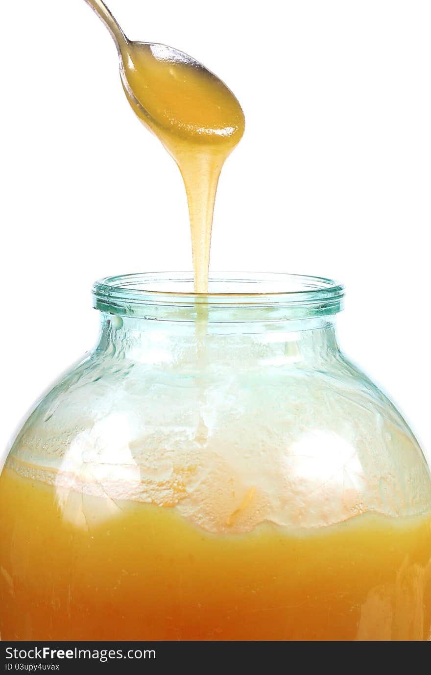 Honey jar and spoon on white background