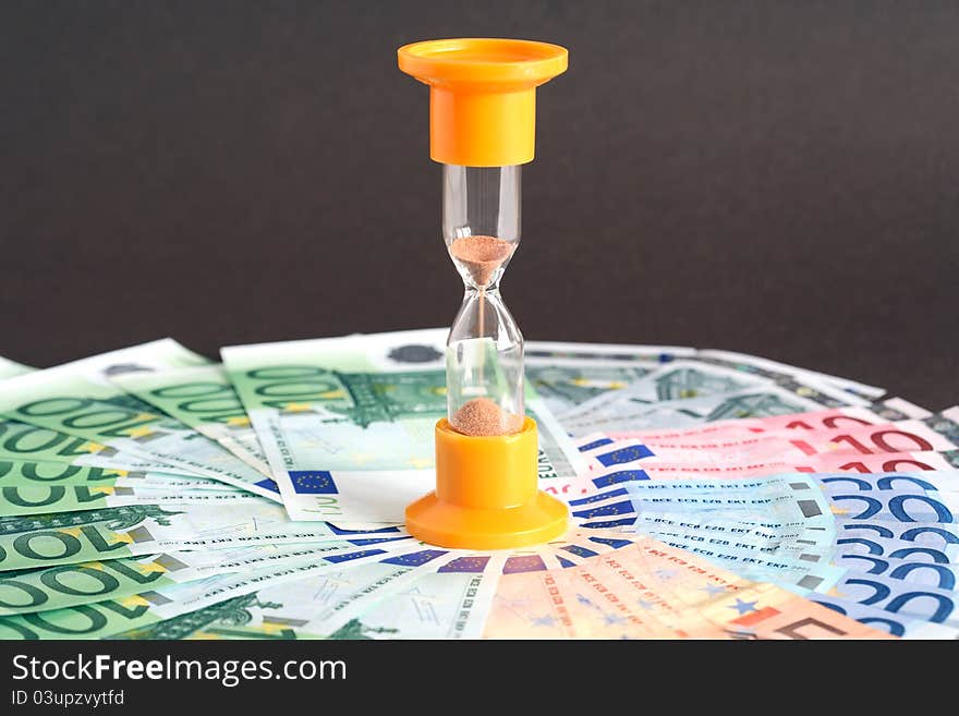 Time is money concept. Hourglass standing on european union currency background