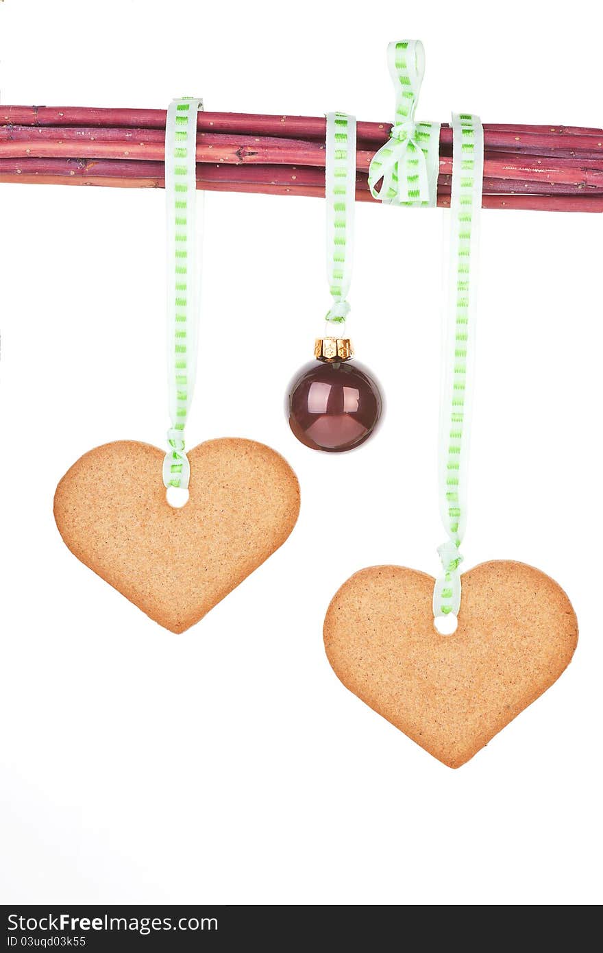 Homemade gingerbread hearts and christmas ball hanging from branches isolated over white background. Traditional christmas concept. Homemade gingerbread hearts and christmas ball hanging from branches isolated over white background. Traditional christmas concept.