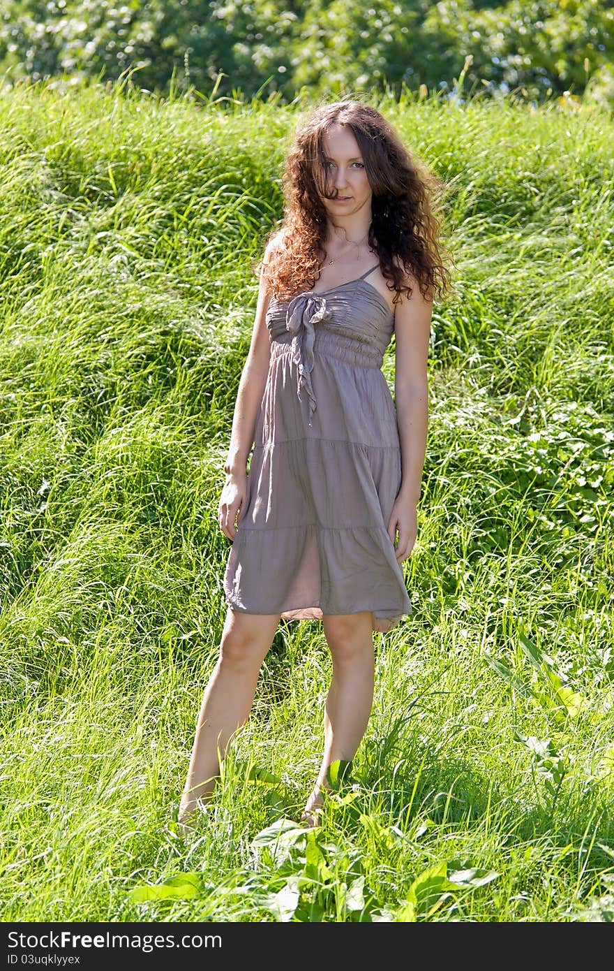 Beautiful girl standing against a background of green grass. Beautiful girl standing against a background of green grass