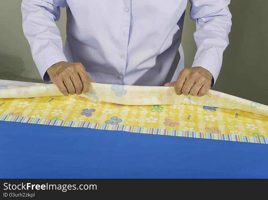 A woman rolling fabric to create a tubular pillow case.