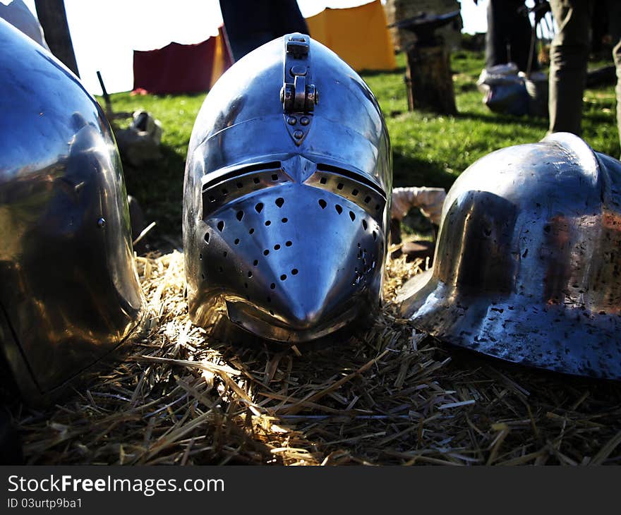 Suit of armor. Medieval metal helmets on the straw. Suit of armor. Medieval metal helmets on the straw