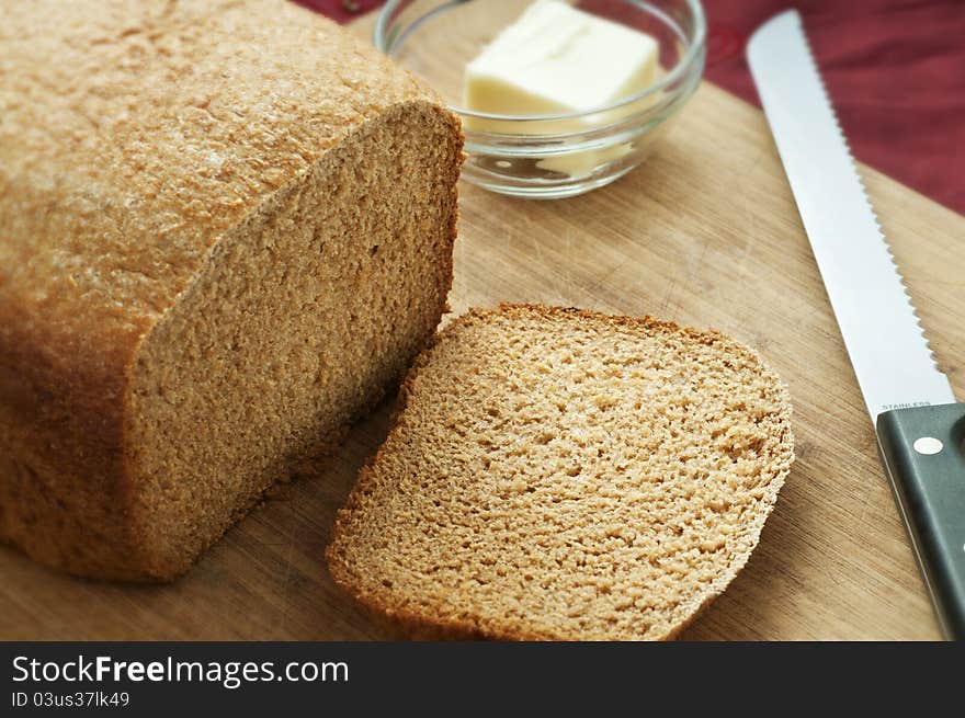 Whole wheat loaf of bread sliced with ramekin of butter. Whole wheat loaf of bread sliced with ramekin of butter