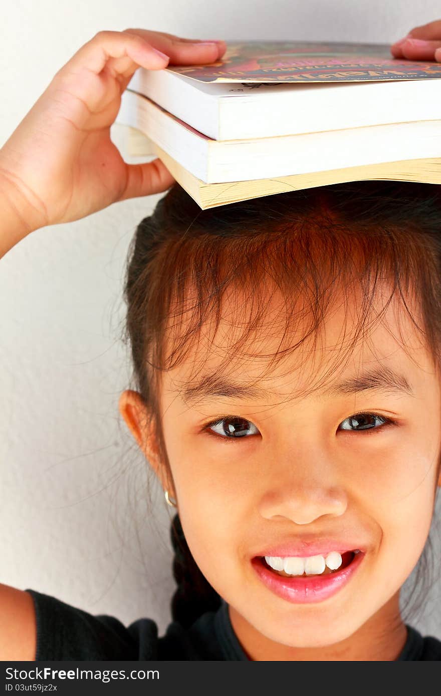 A beautiful smiling student with lots of books on her head