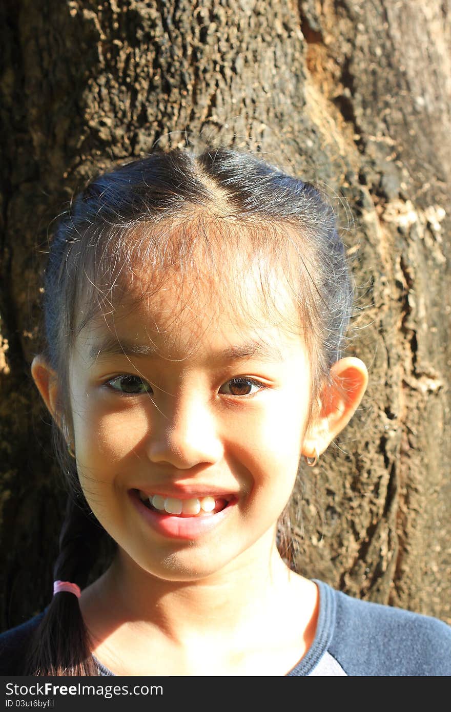 Little girl standing near a tree. In the early morning sun. Little girl standing near a tree. In the early morning sun