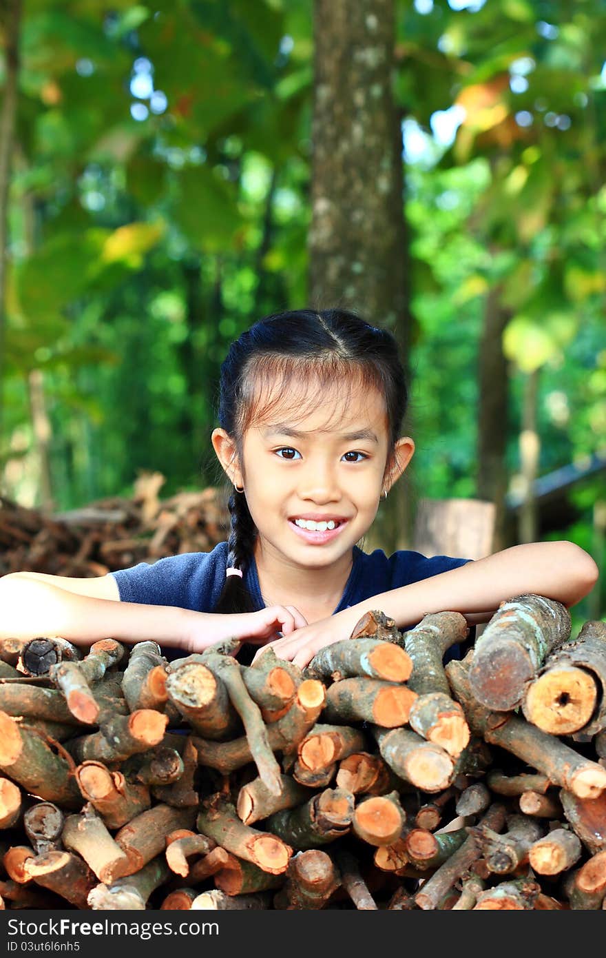 Little girl standing near a pile of firewood in the park. Little girl standing near a pile of firewood in the park