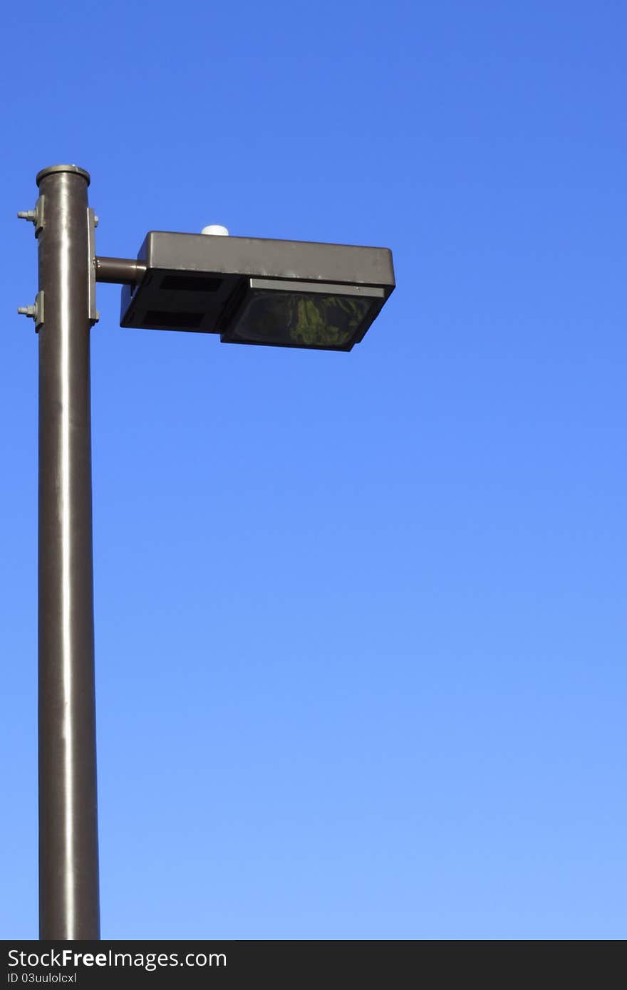 Public street light tall in a morning bright blue sky. Public street light tall in a morning bright blue sky.