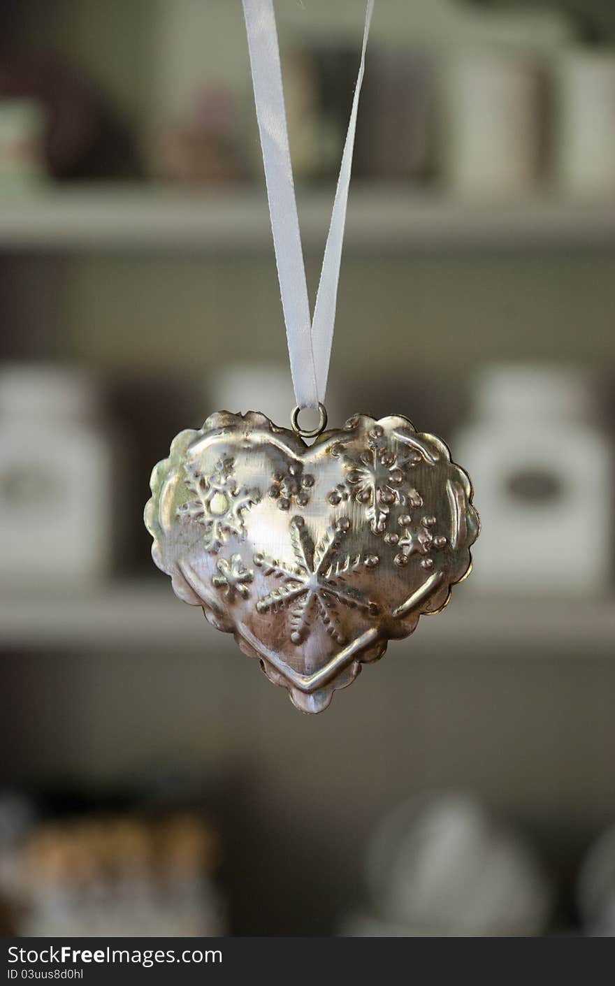 White ribbon with a iron heart with punched stars before a kitchen kabinet. White ribbon with a iron heart with punched stars before a kitchen kabinet