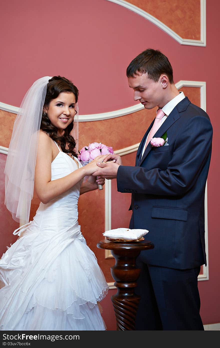 Elegant groom wears a wedding ring a happy bride