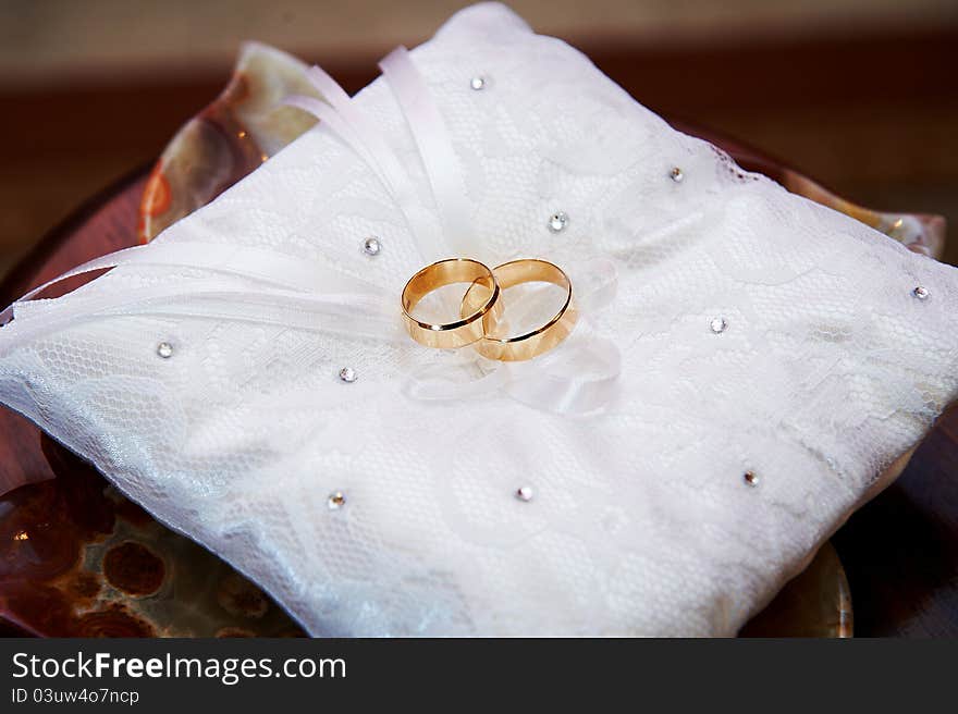 Gold wedding rings on white pillow