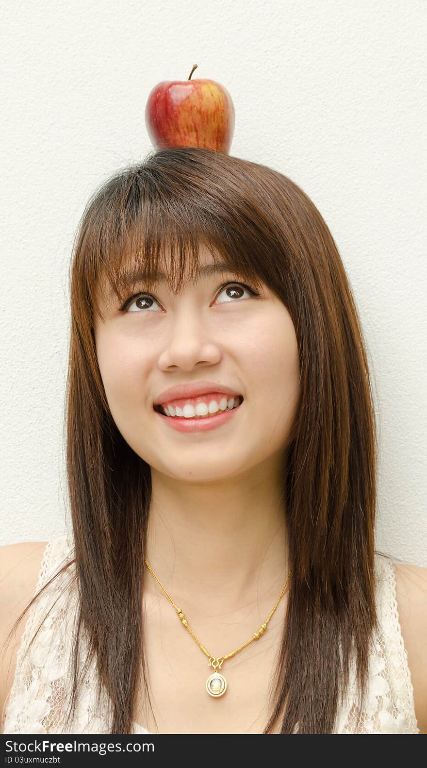 Asian girl look at apple on her head on white background