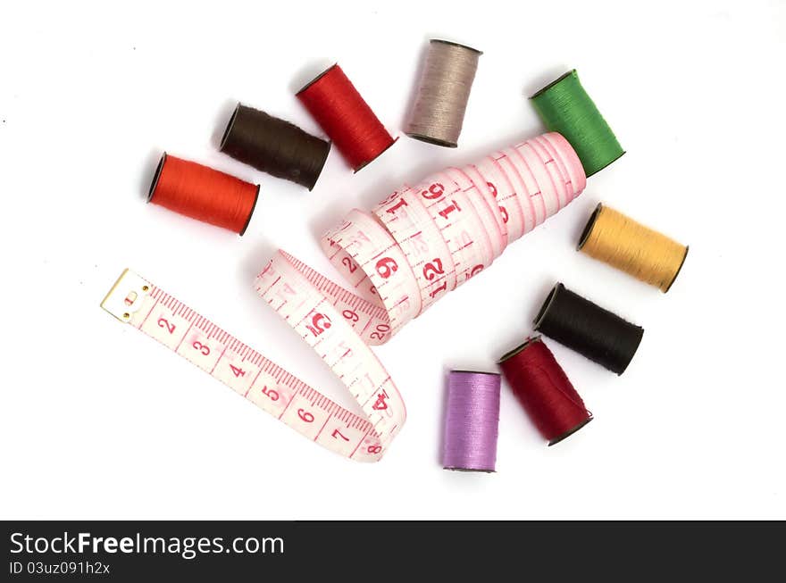 Colorful threads and measuring tape on white background