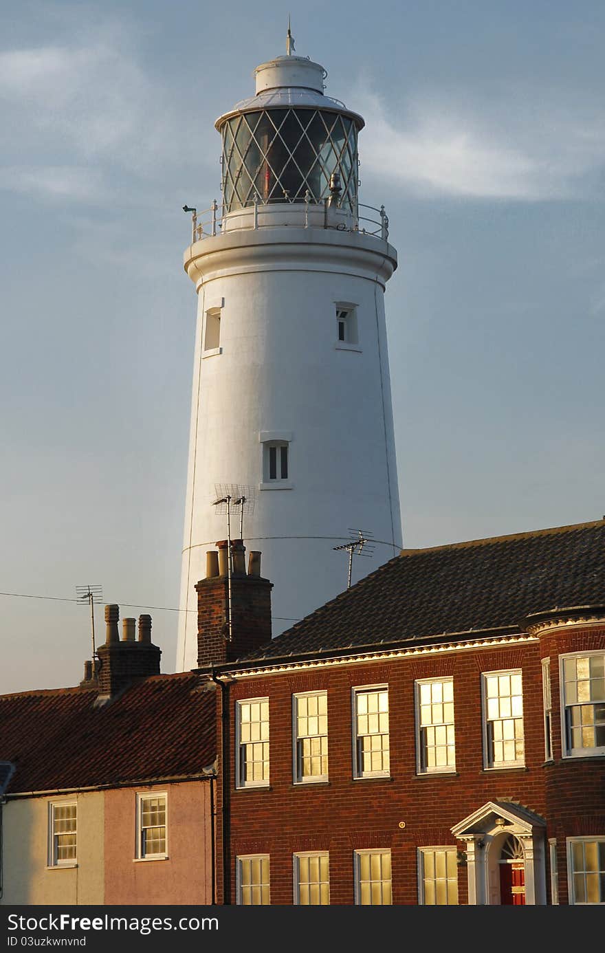 The famous lighhouse looms above houses in golden sunlight on the Suffolk coast. The famous lighhouse looms above houses in golden sunlight on the Suffolk coast