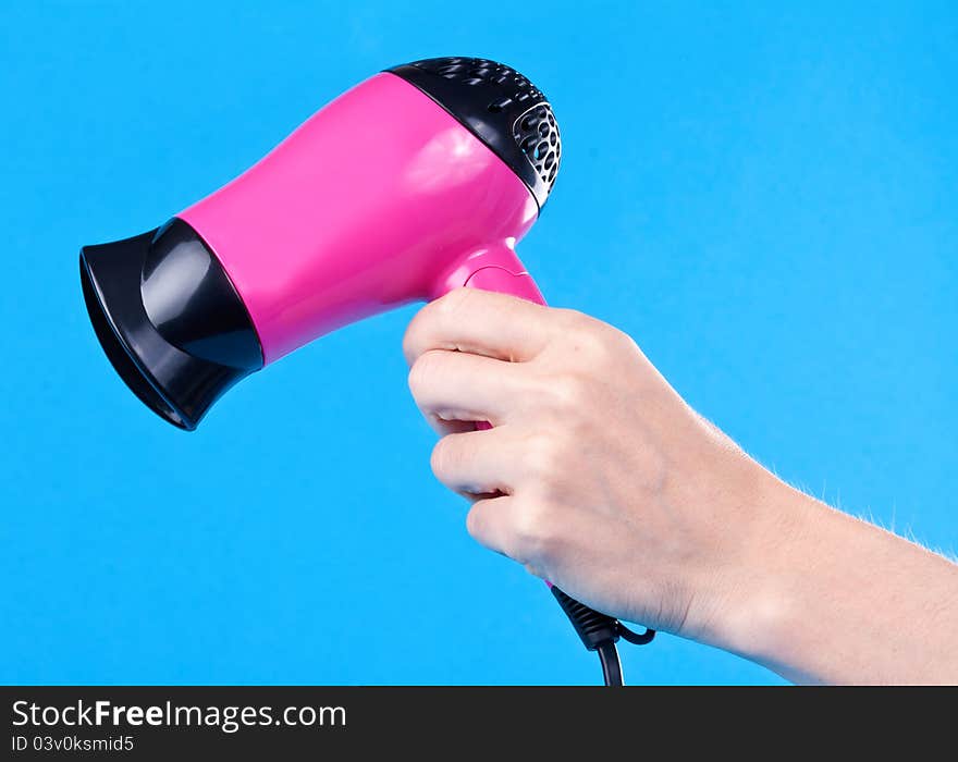 Pink hair dryer in the female hand