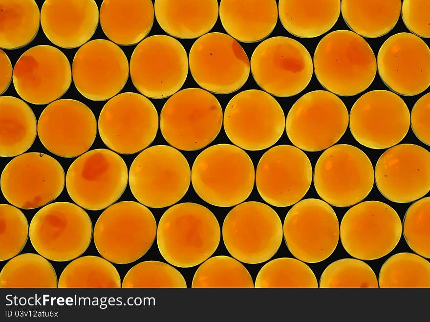 Close-up of orange glass gems on black background.