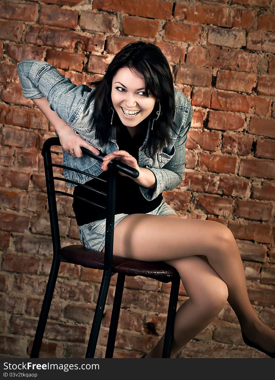 Smiling young woman sitting on a brick wall background