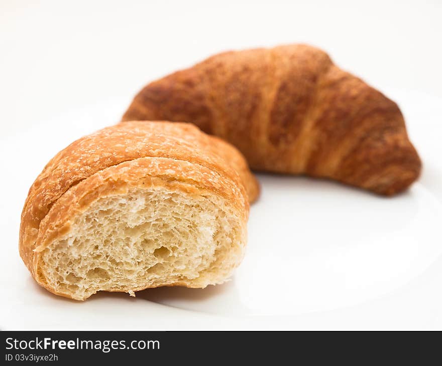 French croissants (one bitten) on a white plate.