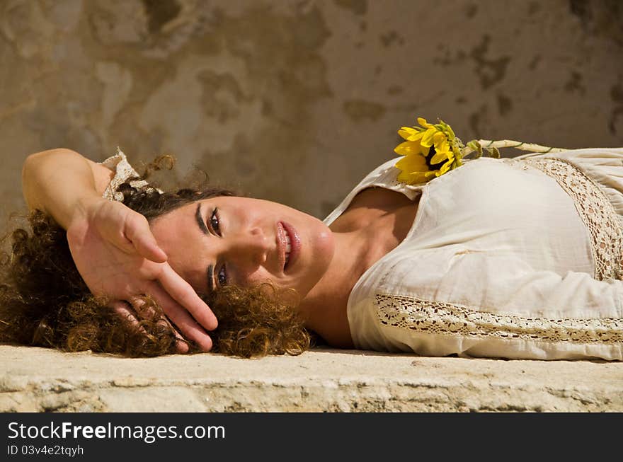 Beautiful Young attractive girl model  lie down on wall and posing for a portrait against an outdoor rock wall. Beautiful Young attractive girl model  lie down on wall and posing for a portrait against an outdoor rock wall.