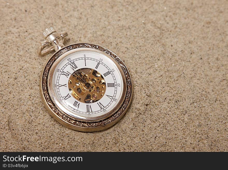 Old pocket watch buried in sand. Lost time concept.