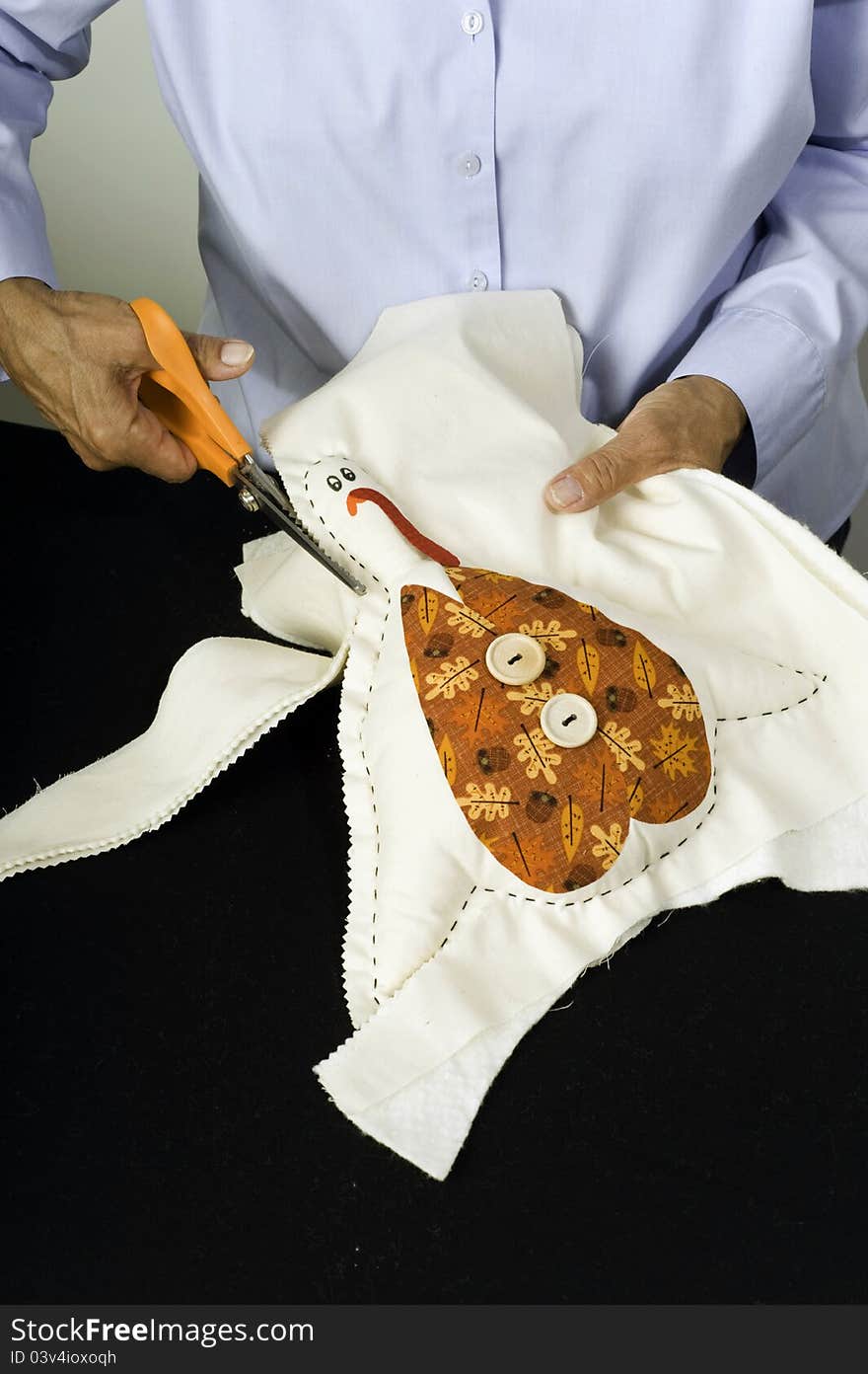 A woman uses scissors to cut shape of turkey. A woman uses scissors to cut shape of turkey.