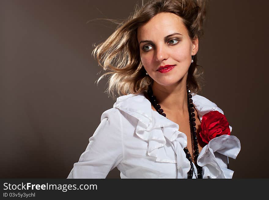 Daydreamed woman in white blouse with red flower with hair on wind